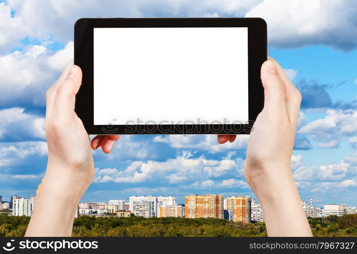 travel concept - hand holds tablet pc with cut out screen and skyline with blue clouds on background