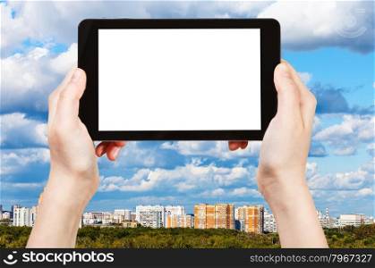 travel concept - hand holds tablet pc with cut out screen and skyline with blue clouds on background