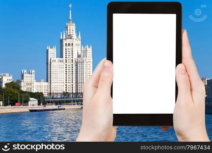 travel concept - hand holds tablet pc with cut out screen and Moscow skyscraper on background