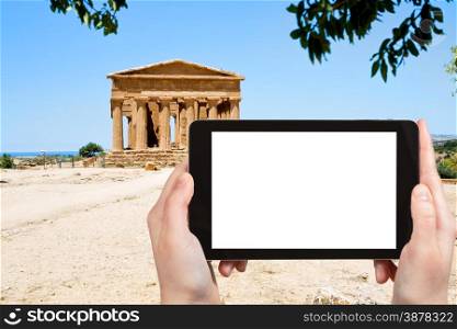 travel concept - tourist photograph ancient Temple of Concordia in Valley of the Temples, Agrigento, Sicily on tablet pc with cut out screen with blank place for advertising logo