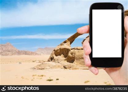 travel concept - tourist photograph Bridge rock in Wadi Rum desert, Jordan on smartphone with cut out screen with blank place for advertising logo