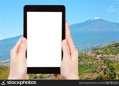 travel concept - tourist photograph Etna volcano and rural gardens on sicilian hills on tablet pc with cut out screen with blank place for advertising logo