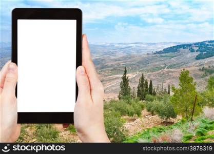 travel concept - tourist photograph Holy Land from Mount Nebo in Jordan on tablet pc with cut out screen with blank place for advertising logo