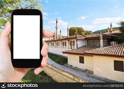 travel concept - tourist photograph moat and walls of Khan&rsquo;s Palace (Hansaray) in Bakhchisaray, Crimea on smartphone with cut out screen with blank place for advertising logo