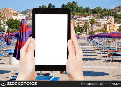 travel concept - tourist photograph urban sand beach in resort town Giardini Naxos, Sicily, Italy on tablet pc with cut out screen with blank place for advertising logo