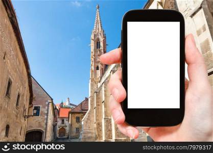 travel concept - tourist photographs Bratislava Hrad castle from Farska street in old town on smartphone with cut out screen with blank place for advertising logo