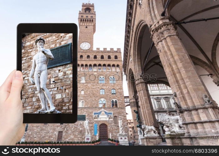 travel concept - tourist photographs David statue near palazzo vecchio in Florence city on tablet in Italy