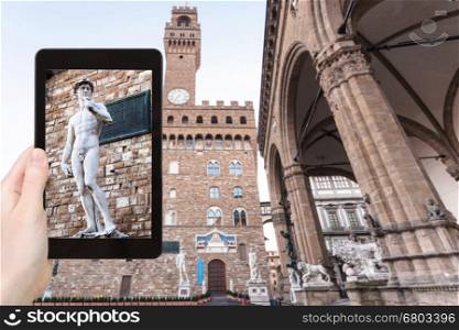 travel concept - tourist photographs David statue near palazzo vecchio in Florence city on tablet in Italy