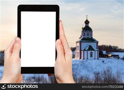 travel concept - tourist photographs of Church of Elijah the Prophet on Ivanovo Hill  Elijah Church  in Suzdal in winter of Russia on smartphone with cutout screen with blank place for advertising