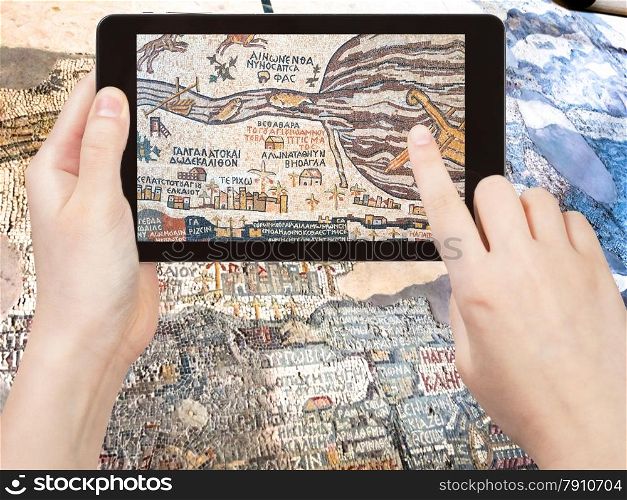 travel concept - tourist shoots photo of ancient byzantine map of Holy Land, Madaba on smartphone, Jordan