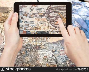 travel concept - tourist shoots photo of ancient byzantine map of Holy Land, Madaba on smartphone, Jordan