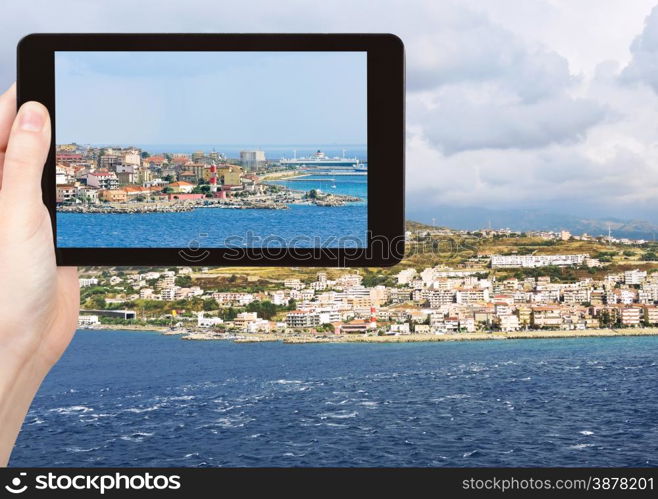 travel concept - tourist snapping photo of town Reggio di Calabria from Strait of Messina, Calabria, Italy on tablet pc