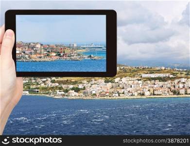 travel concept - tourist snapping photo of town Reggio di Calabria from Strait of Messina, Calabria, Italy on tablet pc