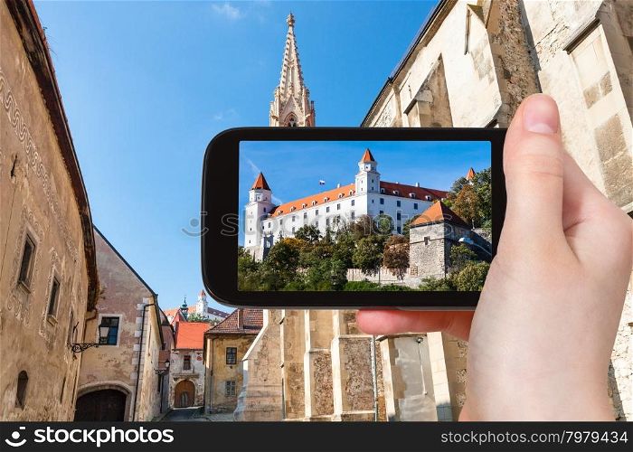 travel concept - tourist snapshot of Bratislava Hrad castle from Farska street in old town on smartphone