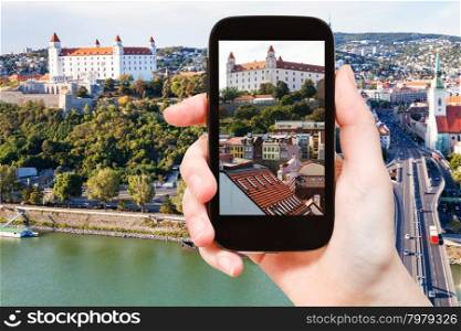 travel concept - tourist snapshot of Bratislava Hrad castle over old town on smartphone