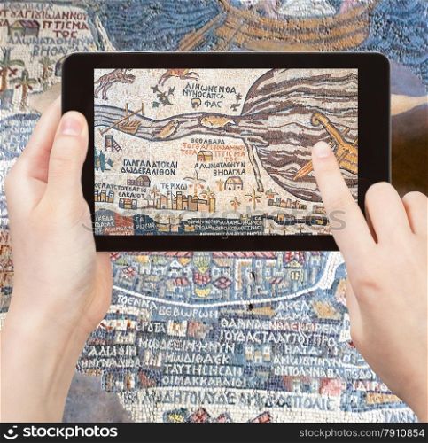 travel concept - tourist takes picture of ancient byzantine map of Holy Land, Madaba on smartphone, Jordan
