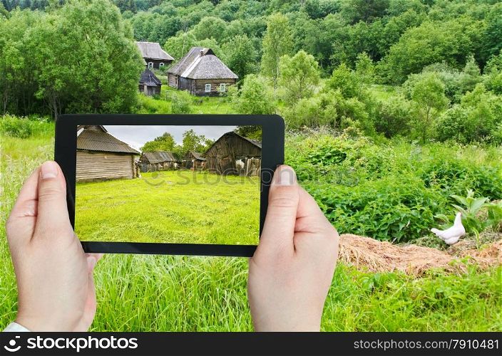 travel concept - tourist takes picture of backyard in peasant household in russian village on smartphone, Smolensk region