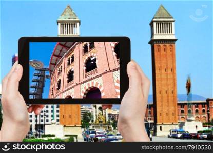 travel concept - tourist takes picture of bullring Arena de Barcelona on Placa Espanya, Barcelona on smartphone,