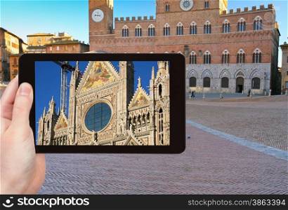 travel concept - tourist takes picture of Cathedral of Siena and Piazza del Campo - Europe&rsquo;s greatest medieval squares, Siena, Italy, on tablet pc