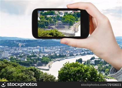 travel concept - tourist takes picture of Deutsches Eck (German Corner) at the confluence of Moselle and Rhine rivers in Koblenz town , Germany on smartphone,
