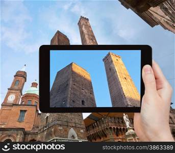 travel concept - tourist takes picture of Due Torri -two tower - symbol of city in Bologna, Italy on tablet pc