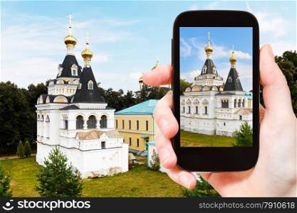travel concept - tourist takes picture of Elizabeth church in Dmitrov Kremlin, Russia on smartphone,