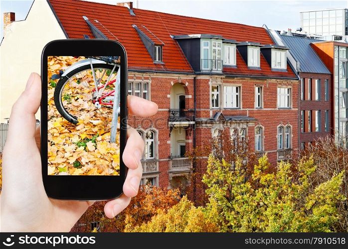 travel concept - tourist takes picture of fallen leaves on street in fall season on smartphone, Berlin, Germany