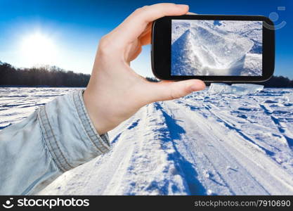 travel concept - tourist takes picture of ski track at snow field in cold winter day on smartphone, Moscow