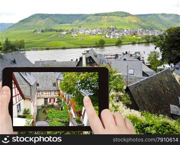 travel concept - tourist takes picture of traditional houses on narrow street in Beilstein village, Moselle region, Germany on smartphone,