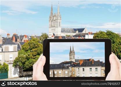 travel concept - tourist takes picture of urban houses and Saint Maurice Cathedral in Angers, France on smartphone,
