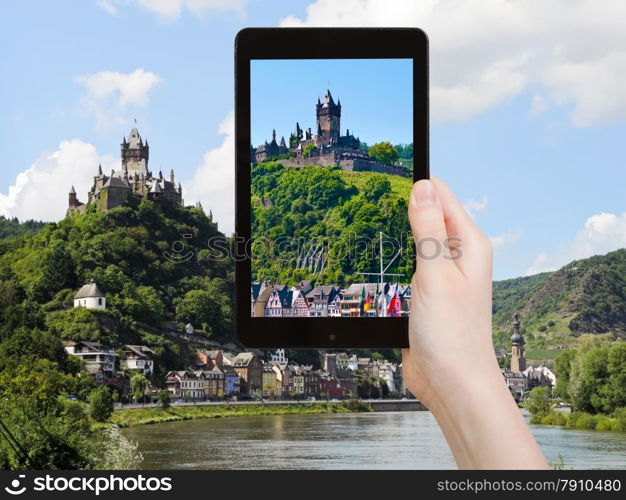 travel concept - tourist takes picture of view of Cochem town on Moselle river and Cochem Imperial castle over town in Germany on smartphone,