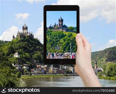 travel concept - tourist takes picture of view of Cochem town on Moselle river and Cochem Imperial castle over town in Germany on smartphone,