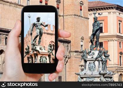 travel concept - tourist taking photo of fountain of neptune in Bologna on mobile gadget, Italy