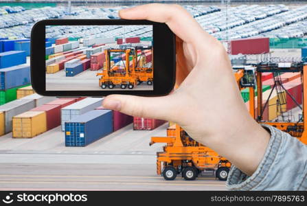 travel concept - tourist taking photo of freight containers in Copenhagen cargo port on mobile gadget