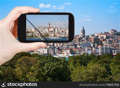 travel concept - tourist taking photo of Galata Tower in Istanbul on mobile gadget, Turkey