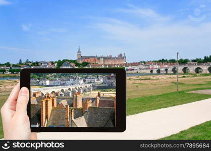 travel concept - tourist taking photo of Gien town in valley of Loire River on mobile gadget, France