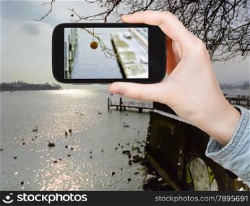 travel concept - tourist taking photo of Lake Geneva in winter on mobile gadget, Switzerland