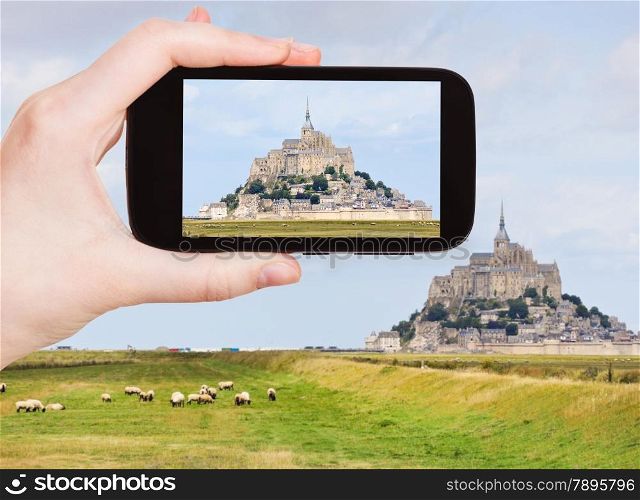 travel concept - tourist taking photo of mont saint-michel abbey, Normandy in summer, France on mobile gadget