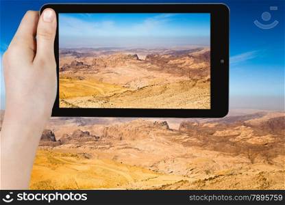 travel concept - tourist taking photo of mountain panorama of Jordan near Petra on mobile gadget