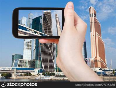 travel concept - tourist taking photo of new Moscow City buildings in summer sunny day on mobile gadget, Russia