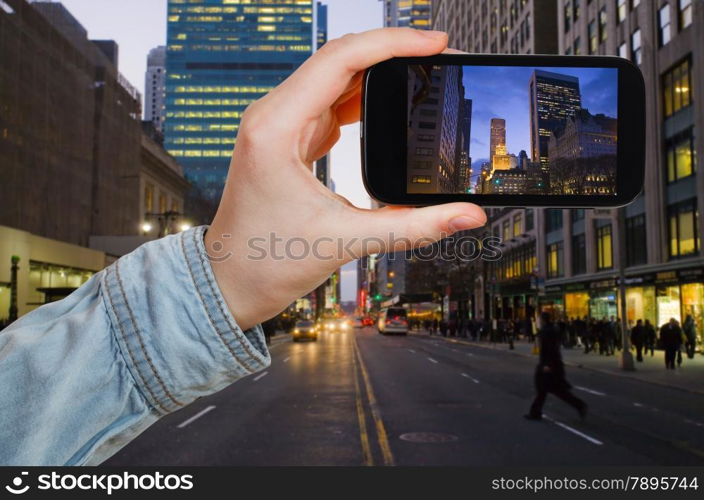 travel concept - tourist taking photo of New York City in evening on mobile gadget