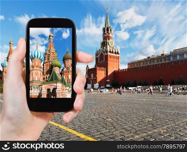 travel concept - tourist taking photo of Red Square in Moscow in summer day on mobile gadget, Russia