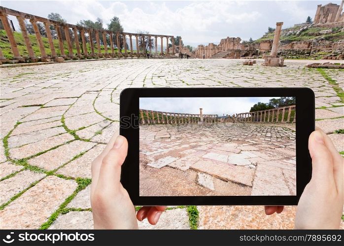 travel concept - tourist taking photo of roman oval forum in ancient town Jerash in Jordan on mobile gadget