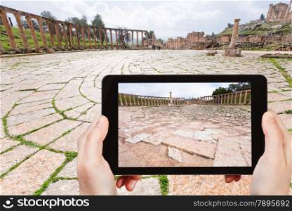 travel concept - tourist taking photo of roman oval forum in ancient town Jerash in Jordan on mobile gadget