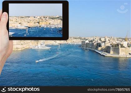 travel concept - tourist taking photo of skyline of Valletta city in summer day, Malta on mobile gadget