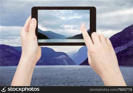 travel concept - tourist taking photo of Sognefjord fjord in Norway in evening on mobile gadget