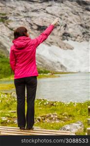 Travel concept. Tourist woman looking and pointing with finger at beautiful mountains landscape in Norway. Woman tourist in norwegian mountains