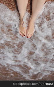 Travel concept - Woman&rsquo;s legs on beautiful tropical beach with pebble sand. Feet on sand and wave in summer time. girl barefoot in ocean water on vacation travel. Feel happy and relax. copy space. Travel concept - Woman&rsquo;s legs on beautiful tropical beach with pebble sand. Feet on sand and wave in summer time. girl barefoot in ocean water on vacation travel. Feel happy and relax. copy space.