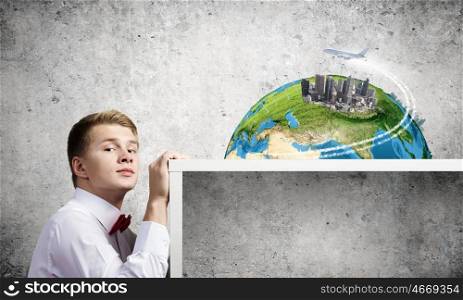Travel concept. Young man pointing at modern city model. Elements of this image are furnished by NASA