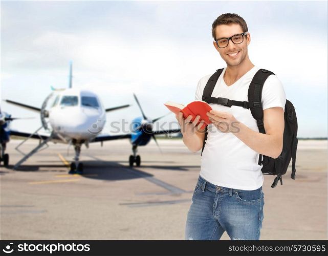 travel, education, tourism and people - smiling student with backpack and book at airport